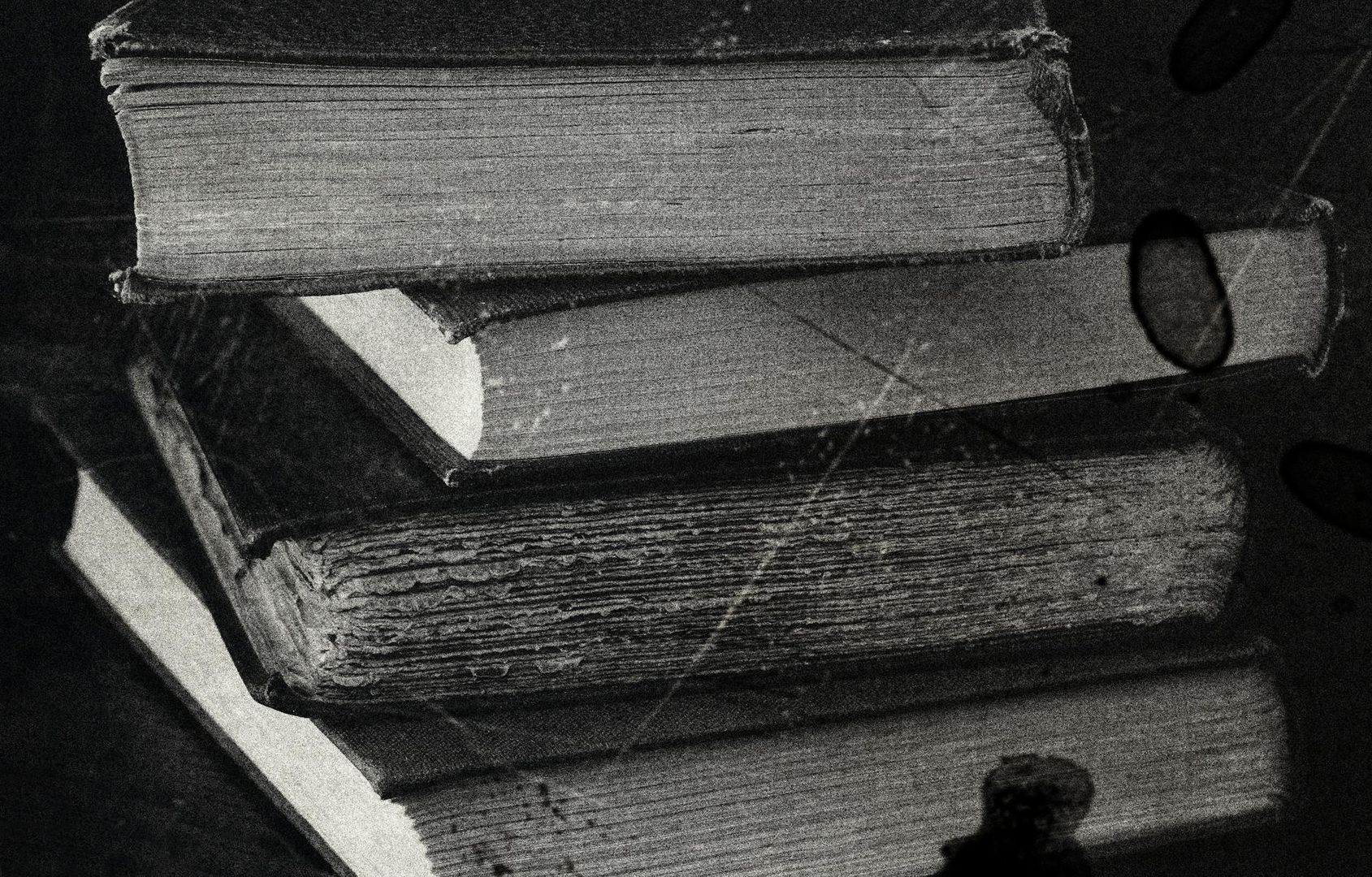 Svartvita gamla böcker staplade, med textur av papper och slitage.